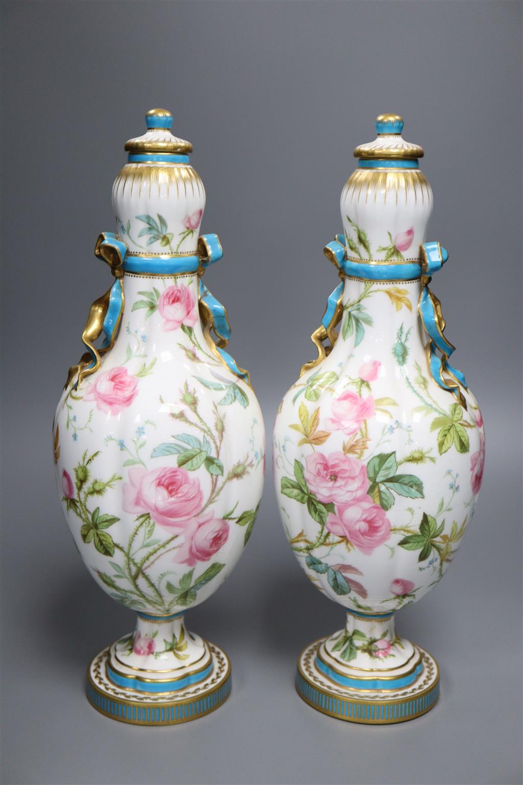 A pair of Minton style ovoid vases and covers, decorated with roses, 37cm